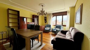 Una sala de estar con una mesa de comedor de madera, dos sillones, un sofá y una araña.