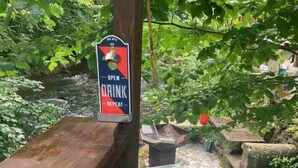 A wooden bench with a sign that reads "OPEN DRINK REPEAT" in a natural setting with greenery. - 2 Bed-sleeps 3-dog Friendly-garden-riverside (Buxton)