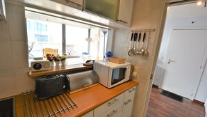 Ett kök med mikrovågsugn, brödrost och köksredskap på bänkskivan.