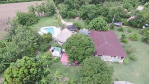 Ein Wohngebiet mit einem Haus, das ein rotes Dach, einen Swimmingpool und eine Struktur mit Strohdach zeigt.