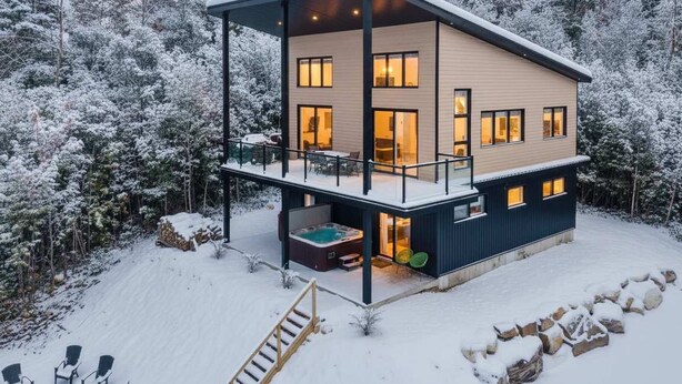 A modern two-story house with a covered patio and a hot tub.