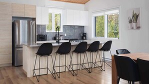 A modern kitchen with a central island, bar stools, and a dining table.