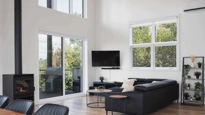 A modern living room with a black sofa, two round coffee tables, a TV, and a fireplace.