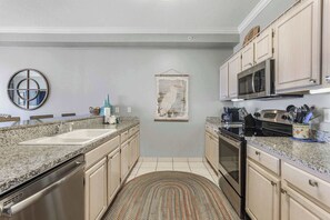 A kitchen with granite countertops, stainless steel appliances, and light wood cabinets. - Grand Pointe 313- gulf front, 3 bedrooms, 3.5 baths, 3rd floor, HUGE balcony (Orange Beach)