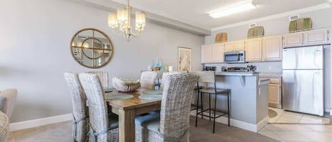 Un coin repas avec des chaises en osier, une table en bois et un lustre.