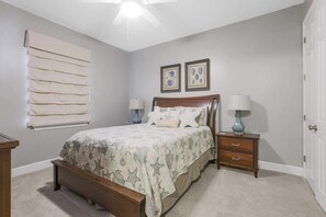A bedroom with a bed, two bedside tables, a nightstand, a ceiling fan, and a window with blinds. - Grand Pointe 313- gulf front, 3 bedrooms, 3.5 baths, 3rd floor, HUGE balcony (Orange Beach)