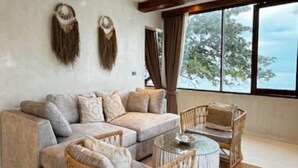 Ein geräumiges Wohnzimmer mit einer großen Couch, einem runden Korbtisch und einem Deckenventilator.