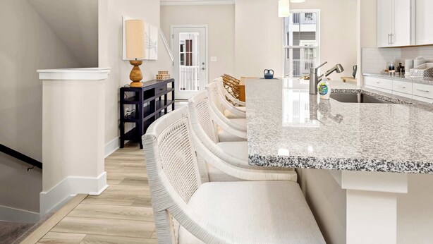 A modern kitchen with a granite countertop, white cabinetry, and a built-in island.