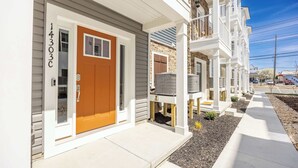 A row of townhouses with a front porch, a mailbox, and a clear sky.