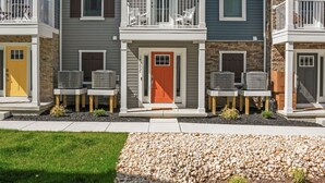 A row of three-story townhouses with balconies, a central entrance, and a small garden area.