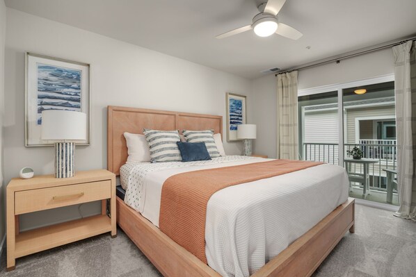A bedroom with a wooden bed, two bedside tables, a ceiling fan, and a balcony with a view.