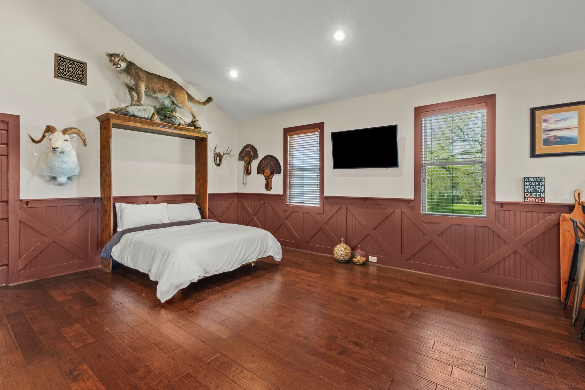 Een slaapkamer met een hemelbed, houten wanden, een opgehangen dierenhoofd en een dier op een rots.