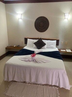 A hotel room with a neatly made bed, a decorative wall hanging, and two bedside lamps. - Located opposite the main square of Boipeba, 300m from Boca da Barra Beach. (Cairu)
