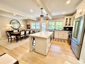 Una cocina amplia con una isla central, armarios blancos y un refrigerador grande.