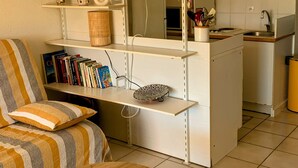 Ein kompakter Wohnraum mit einer Küchenzeile, einem Essbereich mit einem runden Holztisch und einer Couch mit gestreiften Kissen.