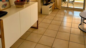 Ein Hotelzimmer mit einem weißen Schrank, einem Spiegel, einem Fernseher, einem Essbereich mit Tisch und Stühlen sowie Blick ins Freie.