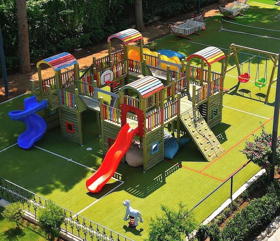Un parque infantil con toboganes, estructuras para escalar y una pequeña estatua.