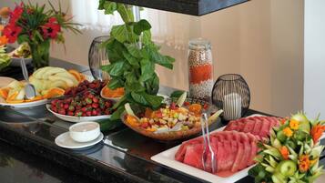 A buffet table with various fruits, vegetables, and a watermelon centerpiece.