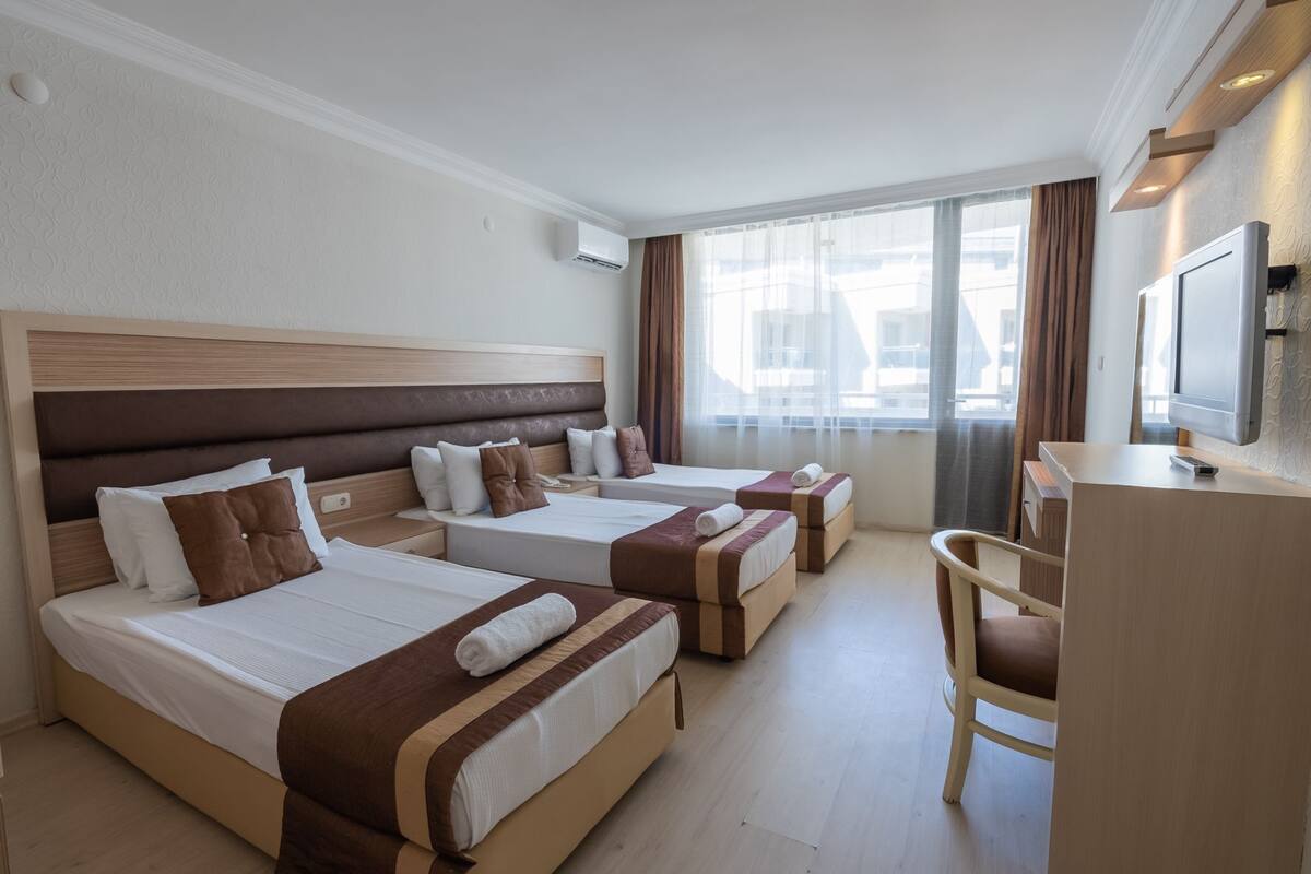 A hotel room with two beds, a desk, and a chair.