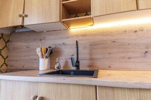 A kitchen with wooden cabinets, a black sink, and a light under the cabinets. - ¡A pie de playa! Apartamento Cap Negret (Altea)