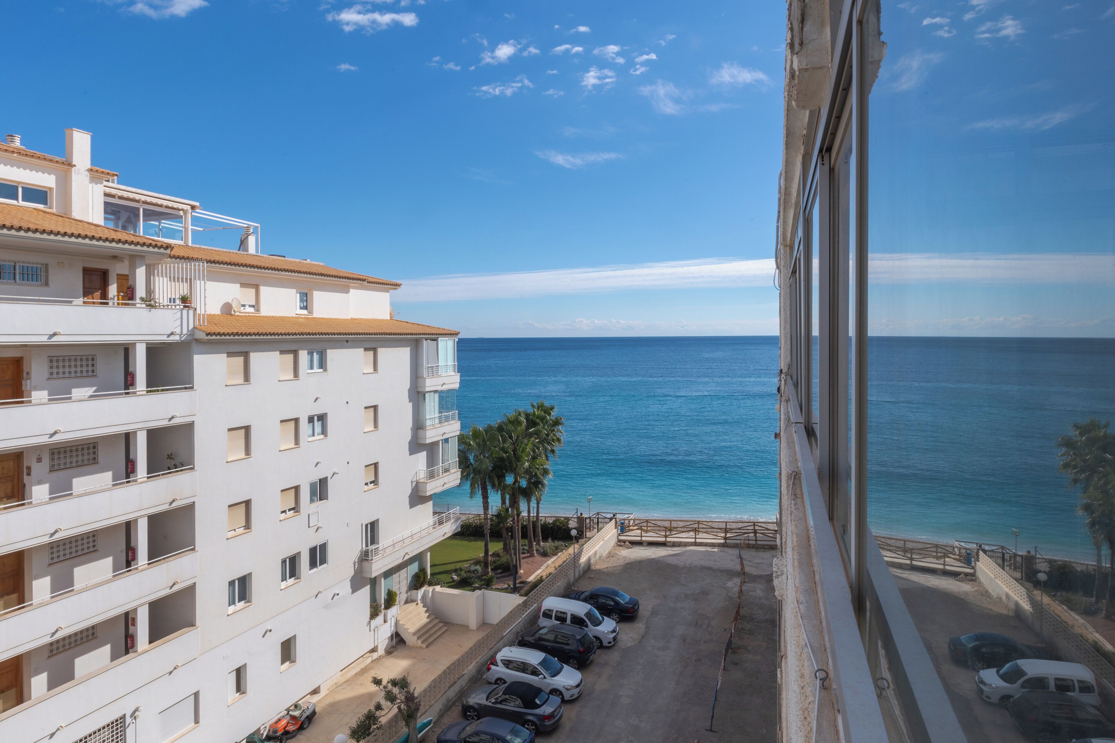 Un edificio de varios pisos con estacionamiento y vistas al mar.
