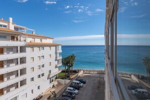 A multi-story building with a parking area and a view of the sea. - ¡A pie de playa! Apartamento Cap Negret (Altea)