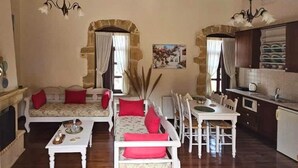 A cozy living room with a sofa set, a dining table, and a kitchen area.