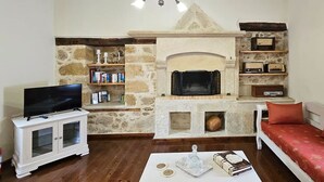 Una sala de estar con chimenea de piedra, televisor, sofá y estantería.