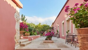 Un patio con escalones que conducen a una zona de estar, rodeado de muros rosados y plantas en macetas.