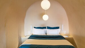 Une chambre à coucher comprenant un lit, deux tables de chevet, un luminaire fixé au mur et un plafond incurvé.