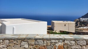 Un bâtiment blanc avec un mur de pierre au premier plan et une vue sur la mer en arrière-plan.