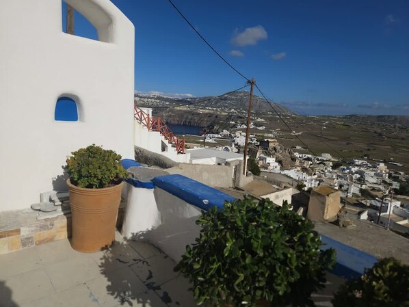 Un edificio blanco con un ventanal azul y una escalera roja que lleva a un pueblo.