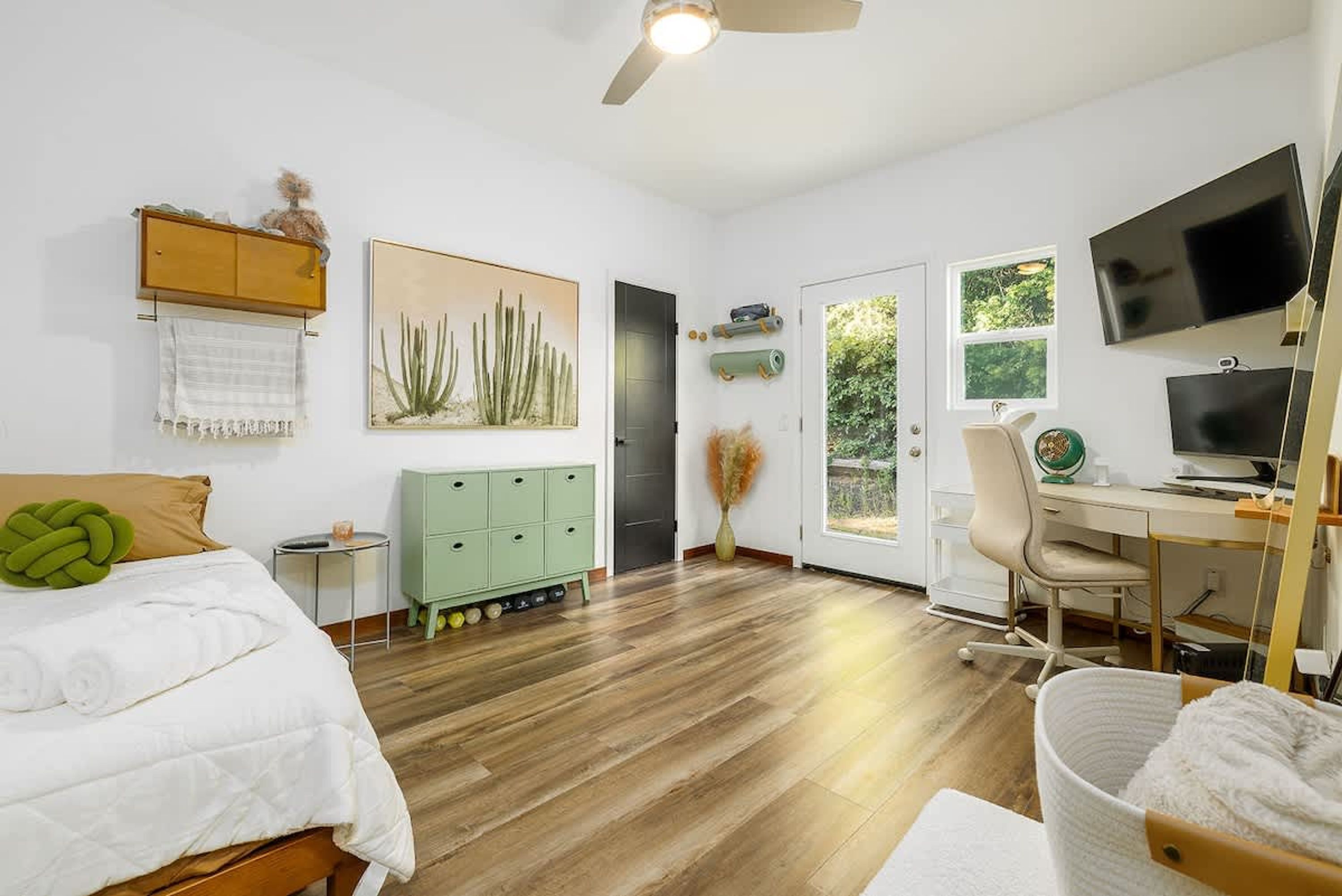 A bedroom with a bed, a desk, a chair, a television, and a window.