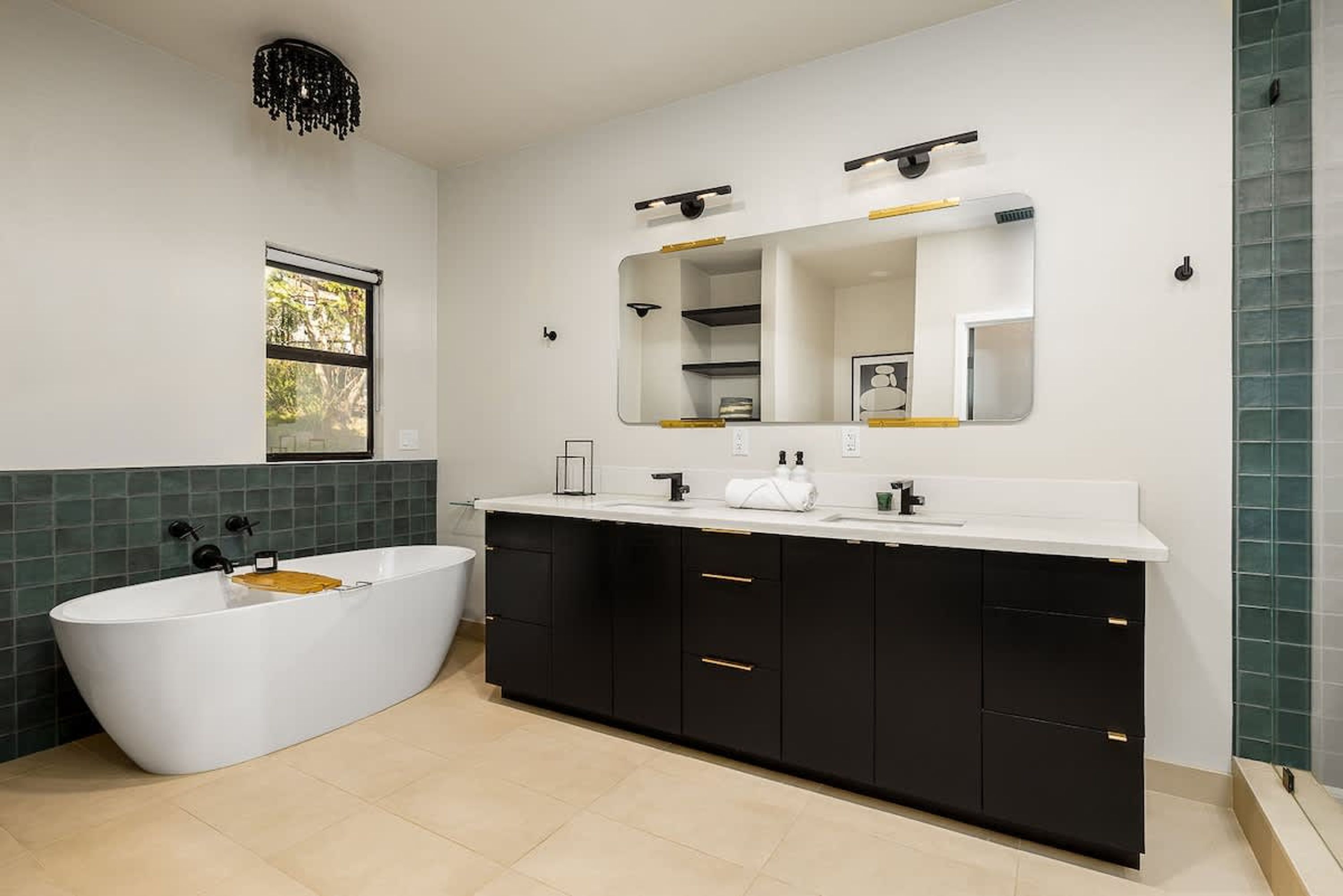 A modern bathroom with a freestanding bathtub, a large mirror, and black cabinets.