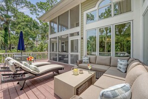 Une terrasse extérieure couverte, aménagée avec une chaise longue, un canapé et une table basse.