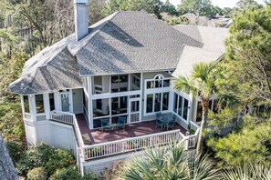 Une grande maison à deux étages, dotée d’un porche couvert, de nombreuses fenêtres et d’une cheminée.
