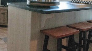 Una cocina con una isla central, taburetes de bar, una ventana y una lámpara de pared.