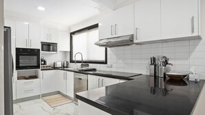 A modern kitchen with white cabinets, a black countertop, and stainless steel appliances.