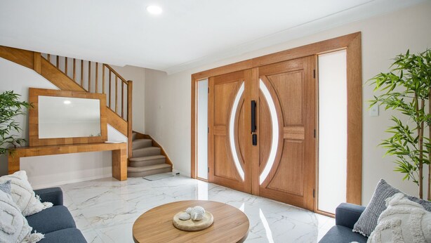 A modern living room with a wooden staircase, a large sliding door, and a marble floor.