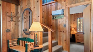 A wooden interior with a green chair, a table, a lamp, and a staircase. - RR015 | Lovely Ranch cabin nestled in the woodsy Central Oregon landscape. (Black Butte Ranch)