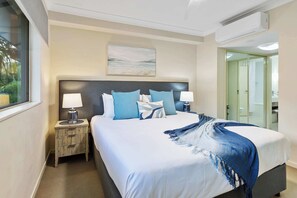 Une chambre d’hôtel avec un grand lit, deux tables de chevet, une fenêtre et une porte donnant sur une salle de bain.