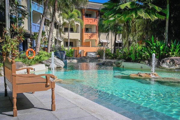 Un espace piscine avec une eau claire, un banc en bois et une bouée de sauvetage.