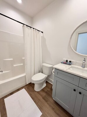 Une salle de bain moderne équipée d’une baignoire, de toilettes et d’un meuble-lavabo.