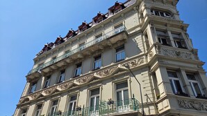 Un edificio de varios pisos con detalles arquitectónicos ornamentales, incluyendo balcones y ventanas decorativas.