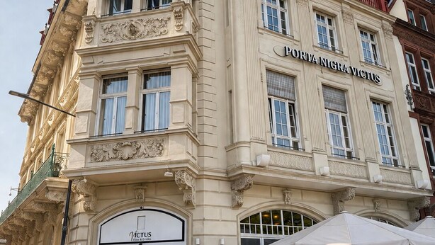 Un edificio histórico con arquitectura ornamentada, una entrada destacada y un letrero que dice 'Portia Nigravictus Hotel'.