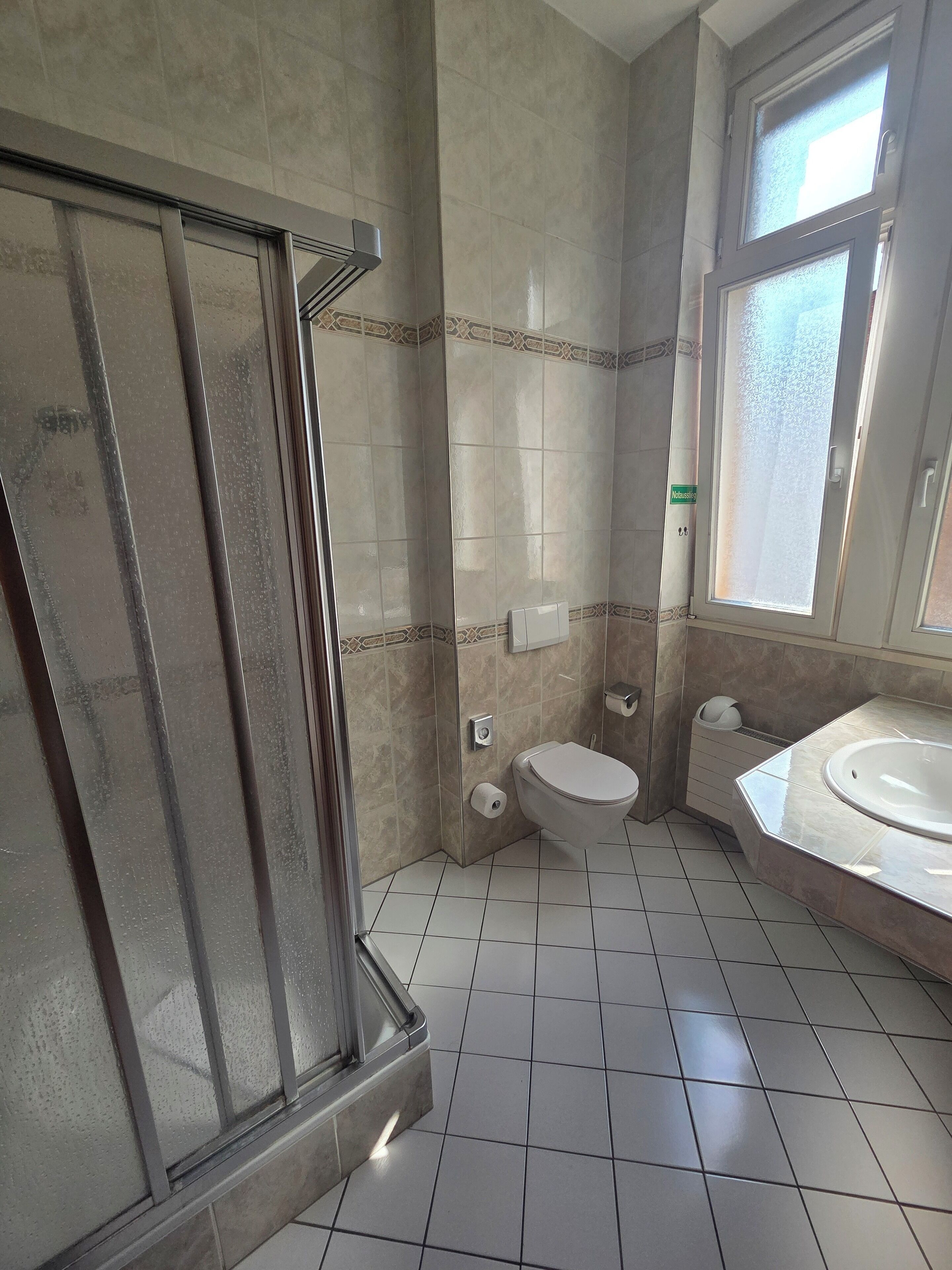 A bathroom with a shower, toilet, and sink.