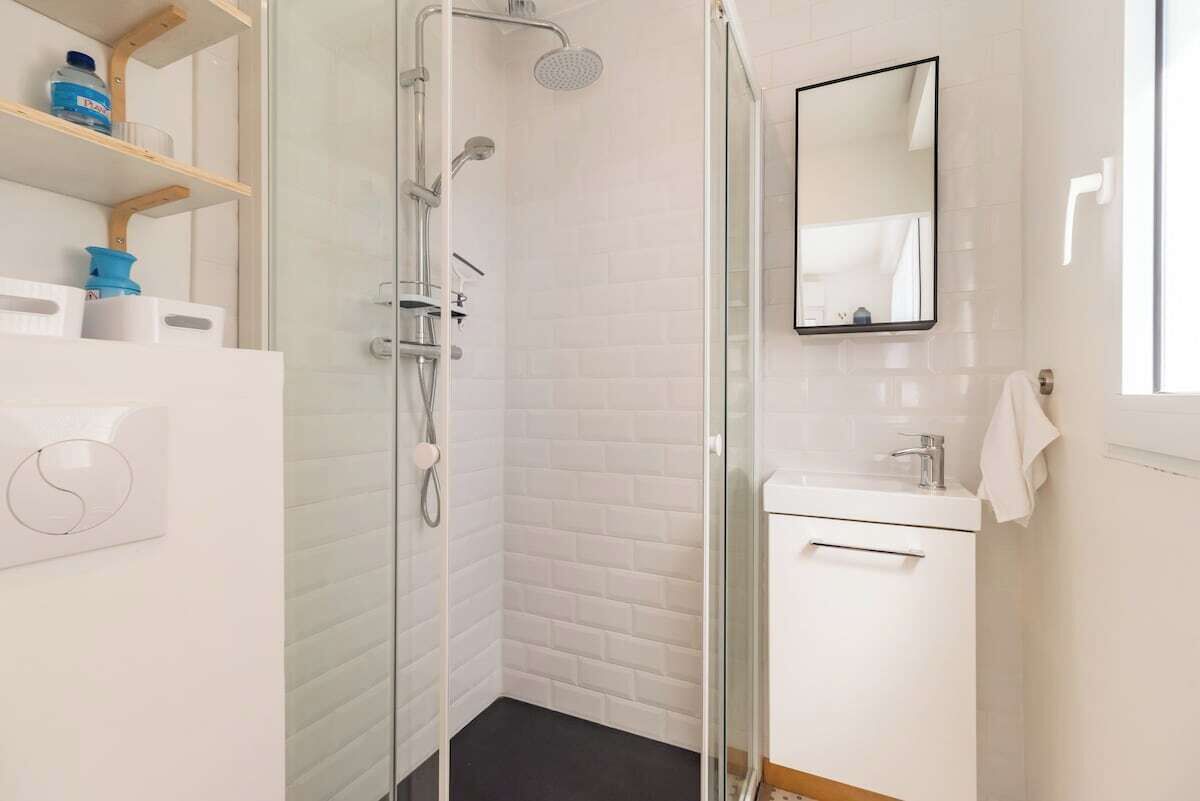 A modern bathroom with a glass shower enclosure, a white sink, and a mirror.