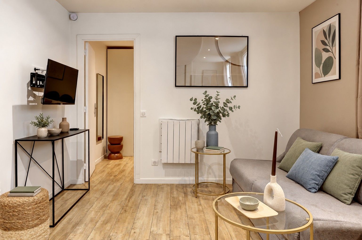 Una sala de estar moderna con un sofá, una mesa de centro y una televisión sobre un mueble.