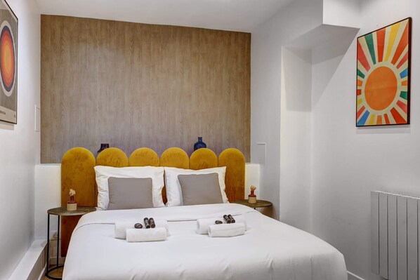 A modern hotel room with a large bed, a wooden headboard, and a sunburst artwork on the wall. - Prestige & confort au cœur de Paris – 8 personnes (Paris)