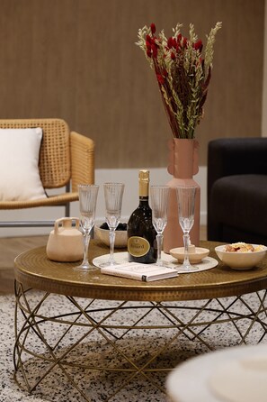 A round table with a bottle of champagne, two glasses, a vase with red flowers, a book, and a bowl of food. - Prestige & confort au cœur de Paris – 8 personnes (Paris)